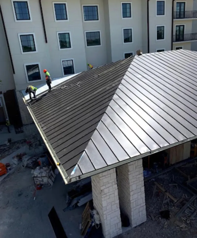 Crew installing standing seam metal roof panels on a commercial project in Delanco